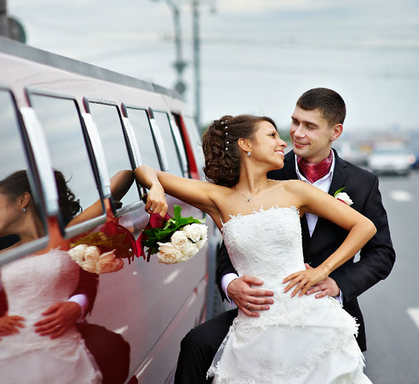 Bride and groom infront of limousine