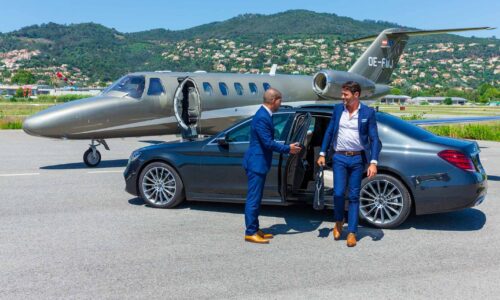 Two professionals standing infornt of a limo and an aeroplane